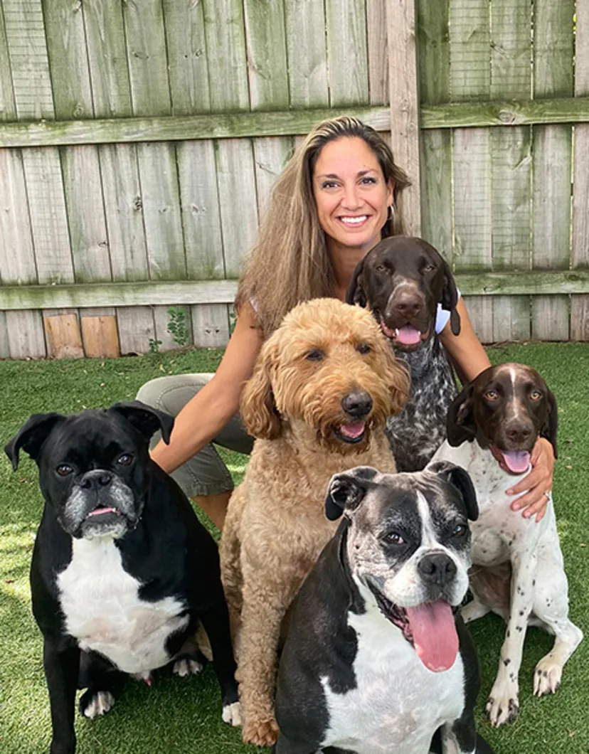 Leslie Shibovich, Multi-Site Practice Manager of Pet Experts Veterinary Group, sitting outside with 5 dogs.